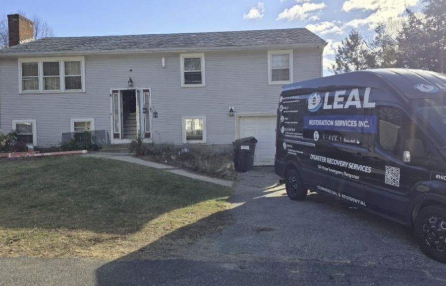Damage restoration services van parked in driveway outside a suburban home
